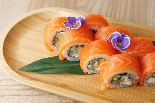 Somon ve salatalıkla yapılan suşi ruloları bambu tabakta güzelce sıralanır. Yenilebilir çiçekler biraz renk katar. Ayar parlak, yemeği ve detaylarını vurguluyor..