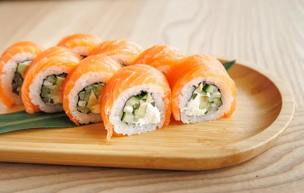 Somon, salatalık ve pirinçli suşi ruloları ahşap bir tabağa konur. Bu düzenek Japon mutfağının tazeliğini ve sanatını gözler önüne seriyor. Yemek için mükemmel..