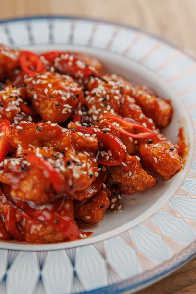 Bu yemek, dilimlenmiş kırmızı biberlerle süslenmiş ve susam tohumlarıyla süslenmiş, zengin bir sosla kaplanmış tatlı ve baharatlı tavuk parçaları içeriyor. Her yemek için mükemmel..