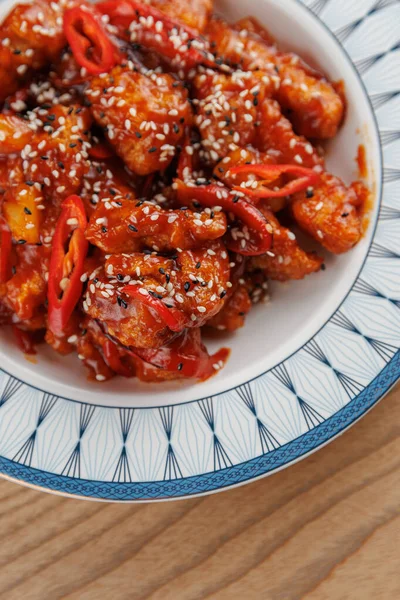 Baharatlı tavuk parçaları kırmızı biber ve susam tohumlarıyla dekoratif bir kasede karıştırılır. Bu yemek canlı renkler ve zengin tatlar sergiliyor, paylaşmak için mükemmel..