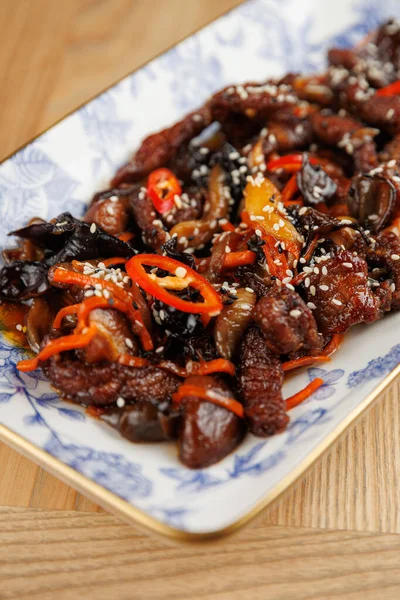 Dilimlenmiş sığır eti renkli sebzeler ve dekoratif servis tabağında otlarla kızartılır. Yemek, yemek sevenlere hitap eden doku ve tatların bir karışımını içeriyor..