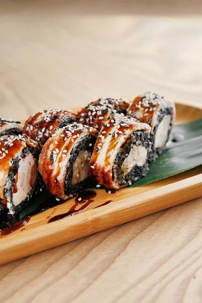 Çeşitli suşi ruloları ahşap bir tabağa düzgünce yerleştirilir. Ekmekte yosunlara sarılmış, soslu ve susamlı malzemeler yer alıyor. Ayar gündelik ve davetkar..