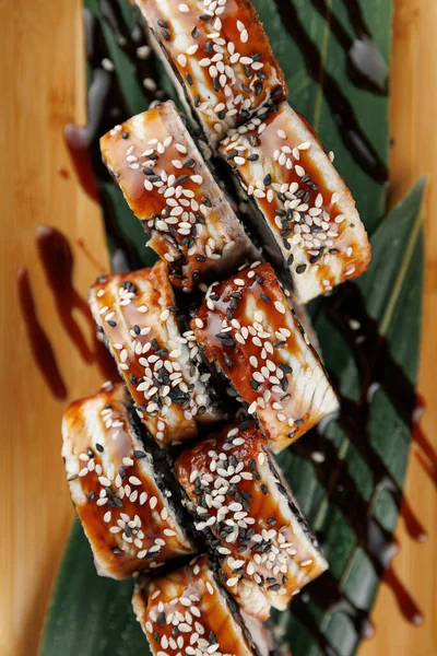 Suşi ruloları bambu yaprakları üzerinde güzelce düzenlenir. Her rulo susam tohumuyla kaplanmış ve lezzetli bir sos serpiştirilmiş. Bu yemek lezzet ve dokuların karışımını sergiliyor, suşi severler için mükemmel..