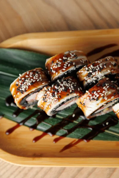 Suşi ruloları yılan balığıyla yapılır ve susam tohumları bambu tabakta sıralanır. Lezzetli bir sos ekmeklerin üzerine serpilmiş, tadını çıkarmaya hazır..