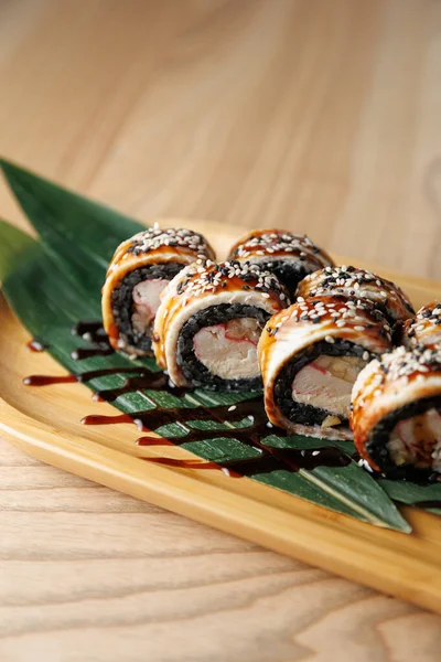 Taze suşi ruloları bambu yapraklı ahşap bir tabakta oturur..