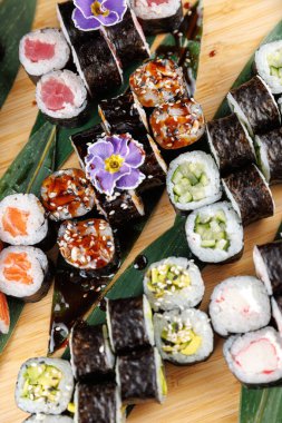 Bir bambu tabağında çeşitli suşi dürümleri düzenlenir. Ekmekte balık ve sebze gibi farklı dolgular yer alıyor. Soya sosu var, tat katıyor..