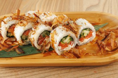 Salatalık ve somonla dolu taze suşi ruloları bambu tabağa konur. Bonito taneleri üzerine serpilmiş, öğle veya akşam yemeği için mükemmel bir lezzet tabağı yaratıyor..