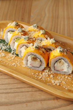 Suşi ruloları ahşap bir tabakta güzelce düzenlenir. İçleri deniz ürünleri ve sebzelerle dolu, soslar ve süslemelerle kaplı, ustaca hazırlanmış Japon yemekleri sergiliyorlar..