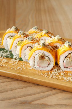 Suşi ruloları ahşap bir tahtada düzgün bir şekilde düzenlenir, canlı renkler ve katmanlı malzemeler sergilenir. Atmosfer sıradan ve davetkar, Japon mutfağı için mükemmel..