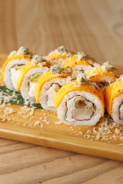 Renkli suşi dürümleri ahşap bir tepside süslenir ve rahat bir yemek ortamında servis edilmeyi bekler..