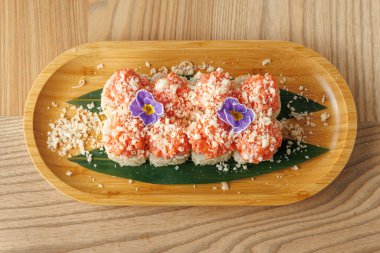 Parlak renkler ve dokular farklı kültürlerden farklı yemek yemeklerini vurgular. Çiçeklerle kaplı suşi ruloları ve gevrek parçalar sıradan bir yemek yerinde ahşap bir tabakta sunuluyor..