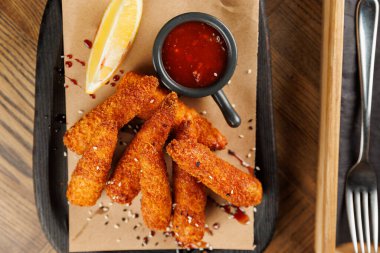 Kızarmış krakerler yanında tatlı sosu ve bir dilim limonla kahverengi bir kağıda konur. Bu yemek lezzet ve dokuların bir karışımını gösteriyor, paylaşmak için ideal..