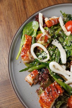 Renkli bir salatada ızgara tavuk parçaları, taze yeşiller ve çeşitli sebzeler gri bir tabakta servis edilir. Bu sağlıklı yemeğin tadını çıkarın..