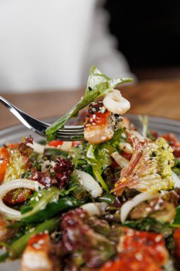 Bir çatal yeşil sebzeler, balıklar ve fındıklı taze salata porsiyonunu kaldırır. Bu sağlıklı yemek yemek masasında servis edilir, hafif bir yemek için idealdir..