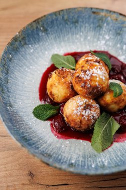 Tatlı böğürtlen sosu ve taze nane ile çevrili mavi bir tabakta Ukrayna usulü kızarmış hamur köftesi servis edilir. Canlı renkler paylaşmak için mükemmel bir yemek oluşturuyor..