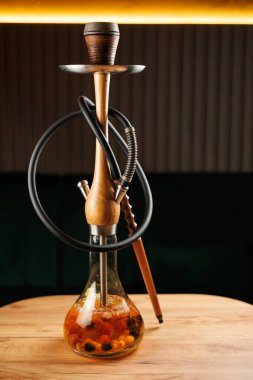 Bir nargile ahşap bir masanın üzerine yerleştirilir. Üs meyve ve tütünle dolu. Ortam sıcak ve davetkar, geceleri arkadaşlarla eğlenmek için mükemmel..