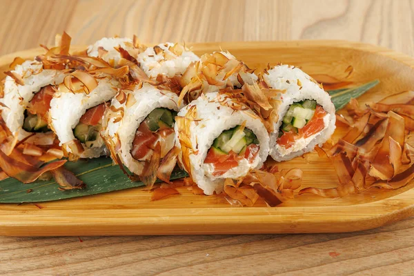 Salatalık ve somonla dolu taze suşi ruloları bambu tabağa konur. Bonito taneleri üzerine serpilmiş, öğle veya akşam yemeği için mükemmel bir lezzet tabağı yaratıyor..