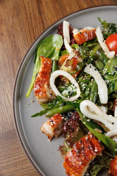 Renkli bir salatada ızgara tavuk parçaları, taze yeşiller ve çeşitli sebzeler gri bir tabakta servis edilir. Bu sağlıklı yemeğin tadını çıkarın..