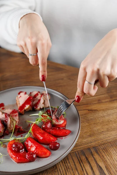 Elleri et dilimleri ve süslemeler yapmak için çatal ve bıçak tutuyor. Ahşap bir masa ve cezbedici bir yemek düzeniyle, sıradan bir ortam..