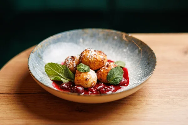 Bir kasede tatlı soslu ve taze nane yapraklarıyla süslenmiş dört kızarmış hamur köftesi var. Bu yemek Ukrayna ve Japon lezzetlerinin karışımını gösteriyor..