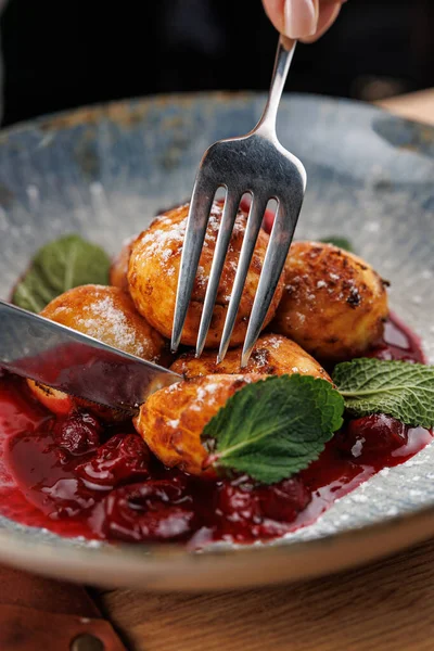 Bir lokanta çatal ve bıçak kullanarak etrafındaki taze nane yapraklarıyla birlikte böğürtlen sosu yatağına yerleştirilmiş altın kızartma köftelerini kesiyor. Ortam sıcak ve davetkar..