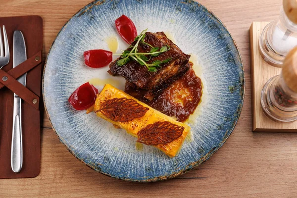 Bir tabak sosla ızgara et ve renkli elementlerle süslenir. Ayarlar, detaylara dikkat ederek küresel mutfağın çeşitliliğini vurguluyor.