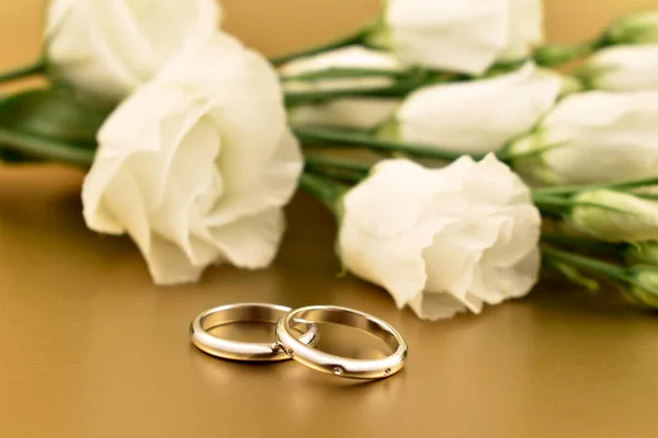 Dois Anéis Casamento Dourados Com Rosas Brancas Fundo Ouro Imagens — Fotografia de Stock