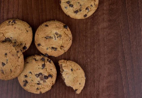 Chocolate chip cookies on a wooden background top view stock images. Sweet chocolate cookies on the table images. American sweet biscuits photo. Cookies on a wooden background with copy space for text