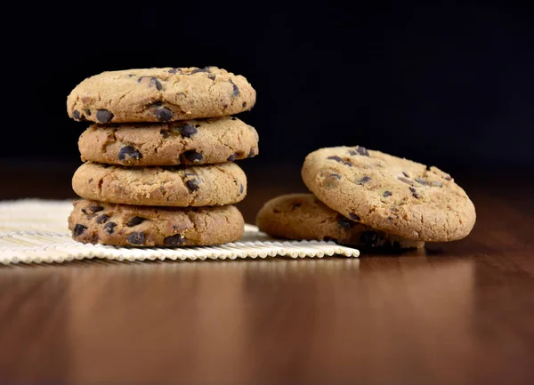 Pile of chocolate chip cookies on a wooden background stock images. Sweet chocolate cookies on the table images. American sweet biscuits photo. Cookies on a wooden background with copy space for text