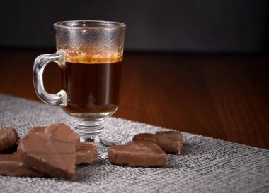 Çikolatalı kurabiyeli bir fincan sade sıcak kahve. Masanın üzerinde bir bardak kahve var. Kalp şeklinde çikolatalı bisküviler ve bir fincan kahve fotoğrafı.