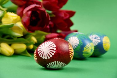 Paskalya yumurtalarını bir buket lale desenli güzel ellerle boyamış. Paskalya renkli yumurtalar yeşil arka planda izole edilmiş ve fotokopi için fotokopi alanı var. Geleneksel Paskalya özgün yumurta resimleri