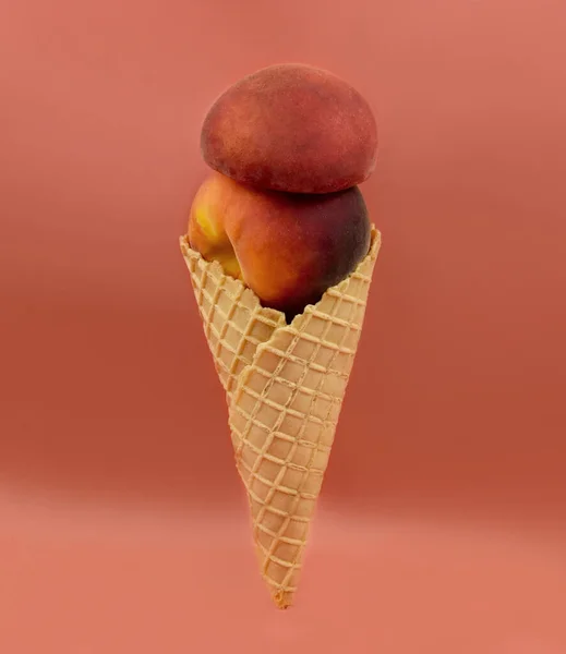 Peach in ice cream cone stock images. Funny peach ice cream isolated on a brown background stock photo. Fresh peaches in a cone images