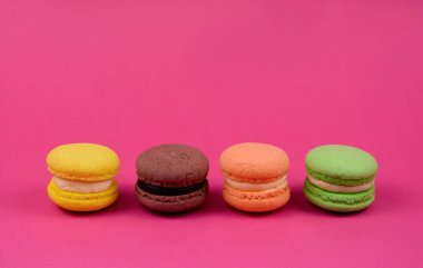Pembe arka planda renkli makaronlar. Renkli Fransız badem kurabiyeleri, metin için kopyalama alanı olan pembe bir arkaplanda izole edilmiş.