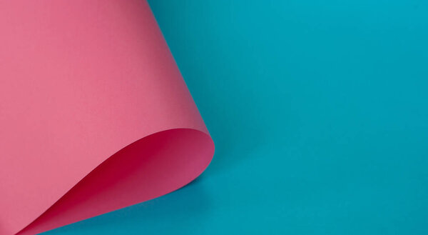 Blue background with rolled pink paper sheet. Minimal concept