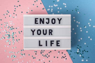Hayatının tadını çıkar - mavi ve pembe arkaplanda ışık kutusundaki metin.