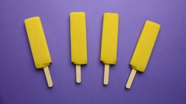 Çubuk mango şerbetindeki sarı dondurma mor arka planda erir. Zaman aşımı