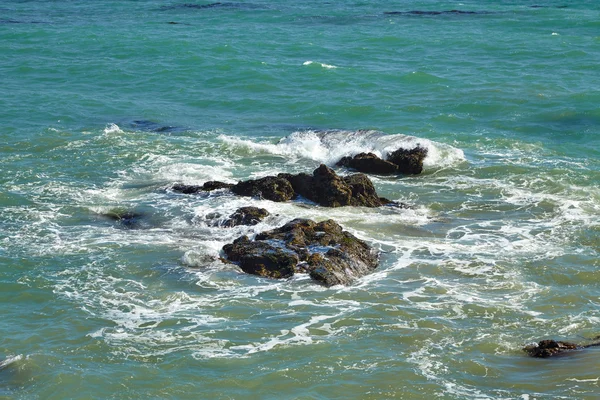 Golven gewonnen tegen kust rotsen op de rotsen — Stockfoto