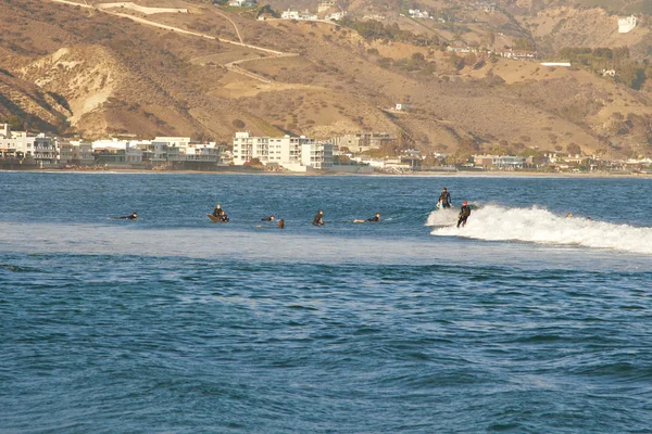 Malibu, California, USA - September 2016: Surfing people ride on the waves