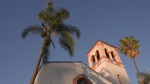 De bladeren van een Californische palmboom zwaaien in de wind tegen de achtergrond van zonsondergang. De gele zon gaat onder. Amerikaanse kerk in de zon. — Stockvideo