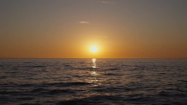 Драматичний захід сонця в океані. палаюче небо і сяючі золоті хвилі. Захід сонця 4k. Червоне небо, жовте сонце і дивовижне море. Літній захід сонця. повільний рух. — стокове відео