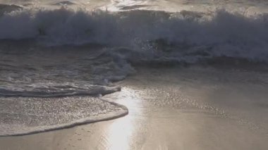 Dramatik okyanus batımı. Yanan gökyüzü ve parlayan altın dalgalar. Gün batımı denizi 4k. Kızıl gökyüzü, sarı güneş ve inanılmaz deniz. Deniz köpüğü sarı kumsala doğru akar. Yaz günbatımı deniz manzarası. Yavaş çekim.