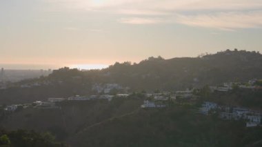 Beverly Hills 'in Panorama' sı. Kamera yavaş hareket ediyor. Güzel manzara yeşil ağaçlar. Zenginlerin lüks evleri. Gün batımında güzel manzara.