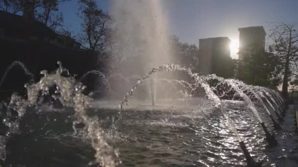 Prachtige fontein op een heldere zonnige dag in slow motion. Waterstralen schitteren in de zon. Heldere spatten verspreiden zich langzaam naar de zijkanten. — Stockvideo