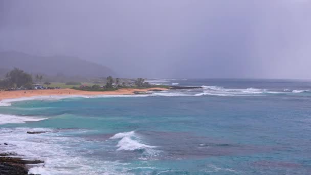 People swim in the turquoise waters of the Tropical Beach. Sandy Beach. Blue Waves of the Pacific Ocean Beats Oahu Island Volcanic Cliffs. Ke One Kula Lookout. Clear sunny day. DCI 4k — Video