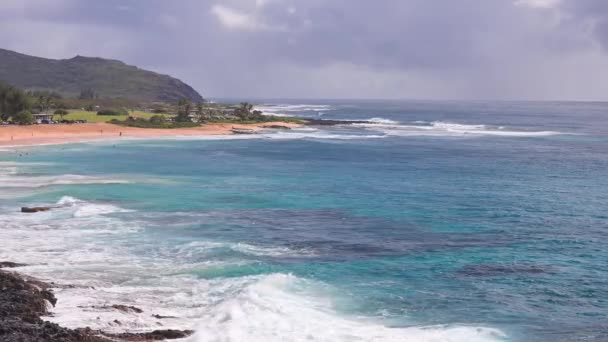 Die Menschen schwimmen im türkisfarbenen Wasser des Tropical Beach. Sandy Beach. Blaue Wellen des Pazifischen Ozeans schlagen die vulkanischen Klippen der Insel Oahu. Ke One Kula Aussichtspunkt. Klarer, sonniger Tag. DCI 4k — Stockvideo