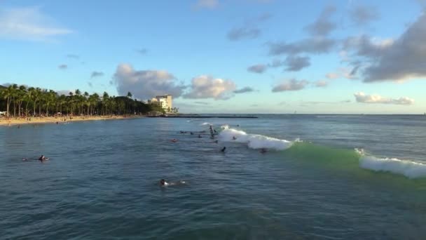 Honolulu, Hawaii - 2021. március 15.: Gyönyörű naplemente a Honolulus Waikiki strandon. A szörfösök hullámoznak. Turisták napozni a strandon. — Stock videók