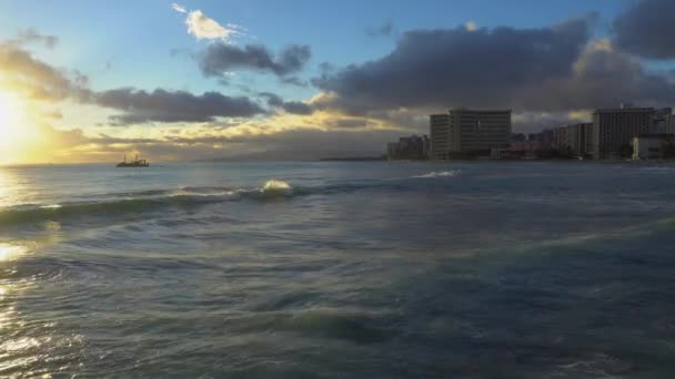Honolulu, Hawaii. Honolulus Waikiki sahilinde muhteşem bir gün batımı. Sörfçüler dalgalara biner. Turistler plajda güneşlenirler.. — Stok video