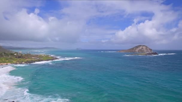 Vista da praia de Makapuu. Ondas de Oceano Pacífico lavar sobre areia amarela da praia tropical. Magníficas montanhas da ilha havaiana de Oahu contra o pano de fundo do céu azul com nuvens brancas. — Vídeo de Stock