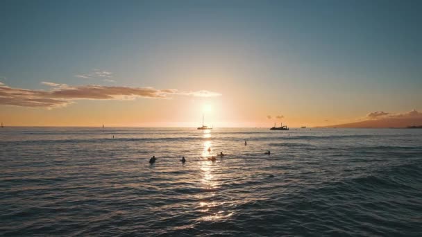 Wspaniałe kolory tropikalnego zachodu słońca. Sylwetki żaglówek pływających na oceanicznym horyzoncie. Surferzy jeżdżą na falach. Oahu, letnie wakacje na Hawajach. Zwolniony ruch. — Wideo stockowe