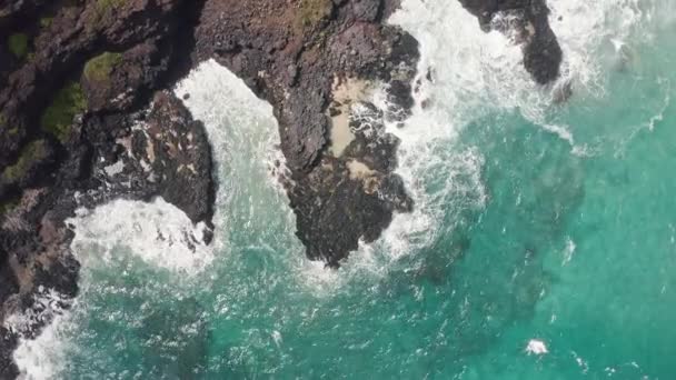 Повітряний постріл з дрона. Верхній вид на скелястий берег океану. Камера обертається навколо 360. Блакитні хвилі Тихого океану вдаряються об скелі. Біла морська піна. Вулканічний пляж на острові Оаху. — стокове відео